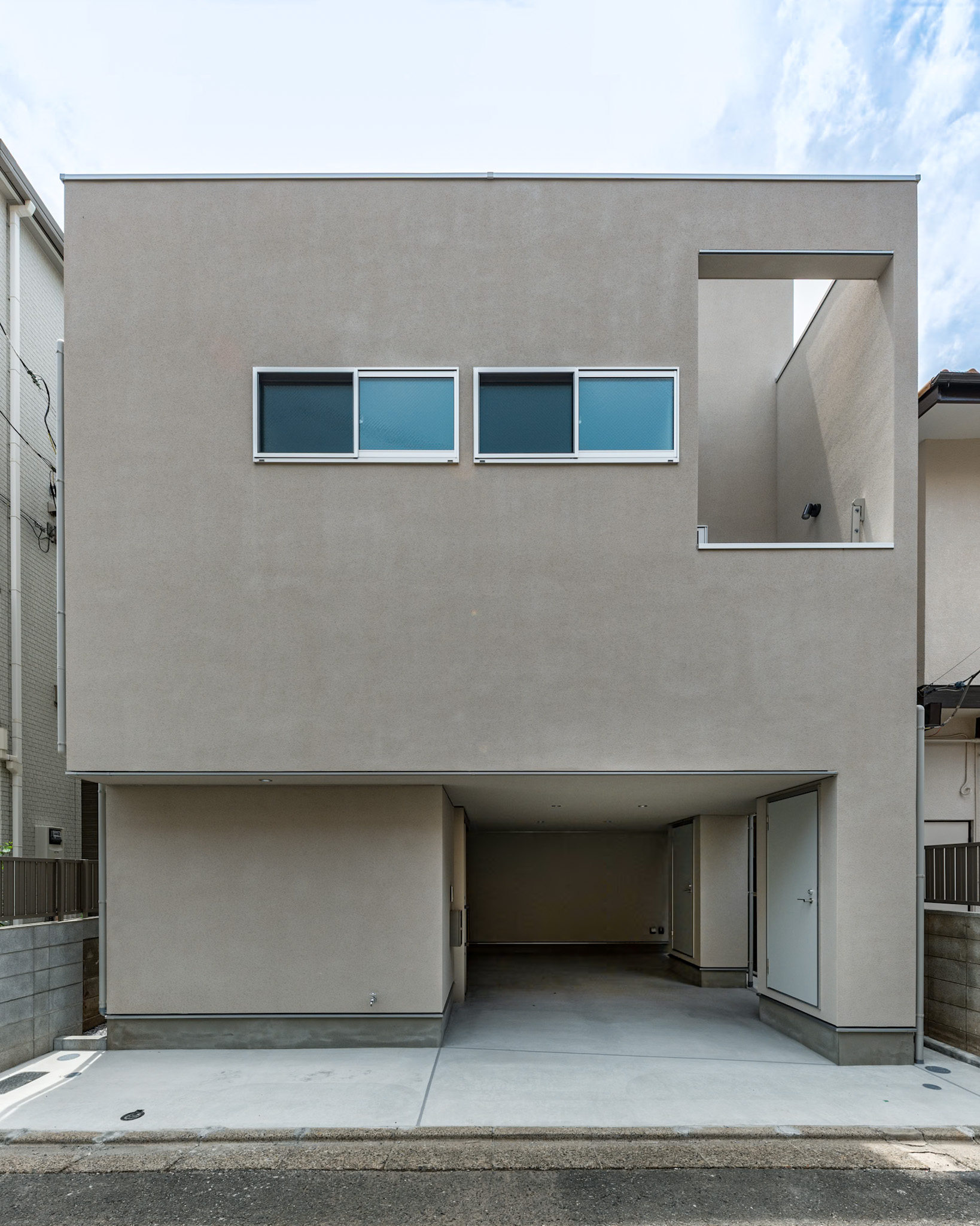 目黒区の注文住宅「中町の家」のプレーンな左官仕上げファサードとインナーガレージ