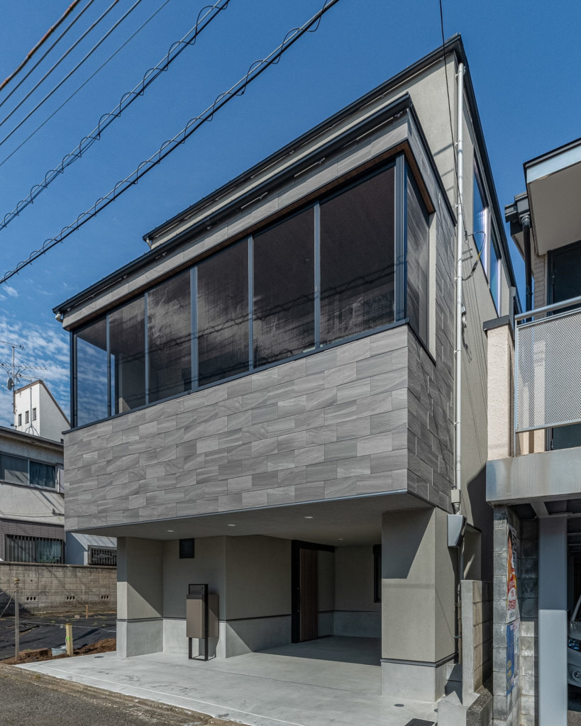 目黒区の注文住宅「目黒本町の家」のモダンな石貼り調ファサードと大きなコーナーサンルーム窓