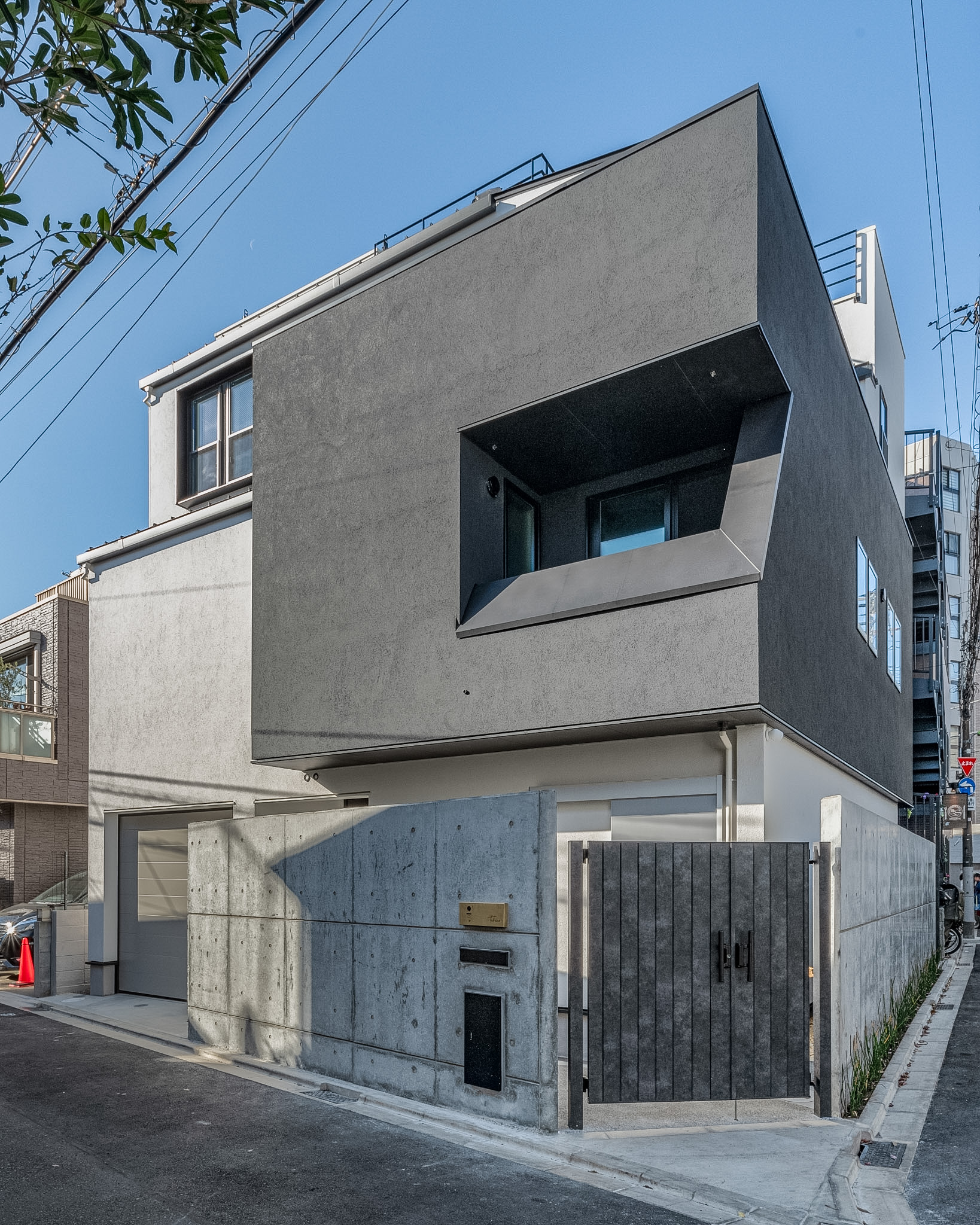 世田谷区の注文住宅「砧の家」の重厚なRC打ち放し塀とチャコールグレーの幾何学ファサード