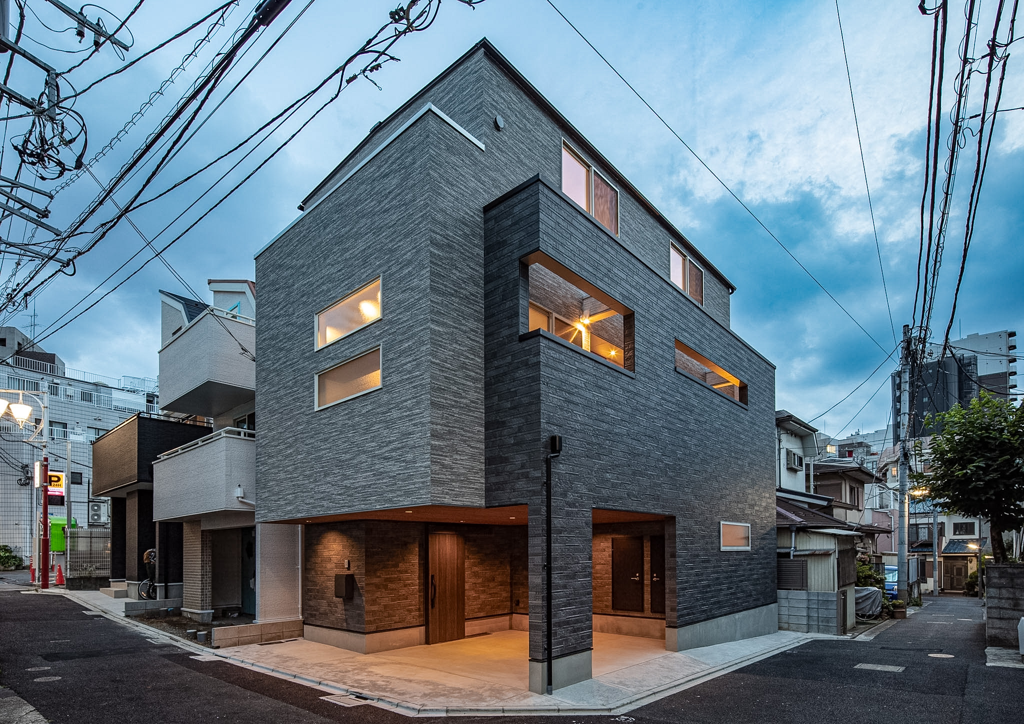 新宿区の注文住宅「西早稲田の家」の重厚な石目調ファサードとビルトインガレージ